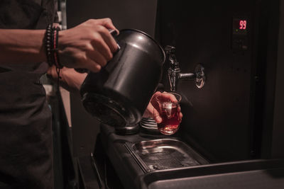 Midsection of man pouring water in coffee at darkroom