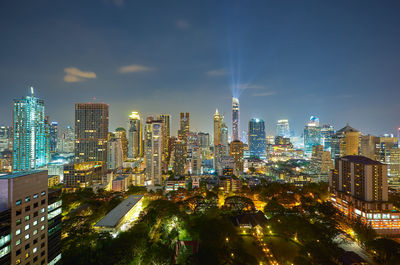 Illuminated modern buildings in city against sky at night