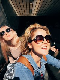 High angle view of happy friends wearing sunglasses on escalator
