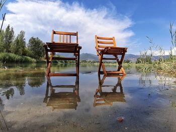 Chair on lake against sky