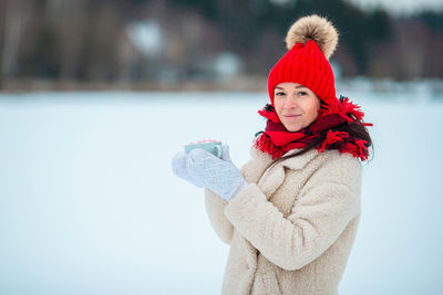 Portrait of smiling young woman standing on snow