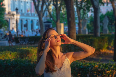 Young woman looking away while standing against trees