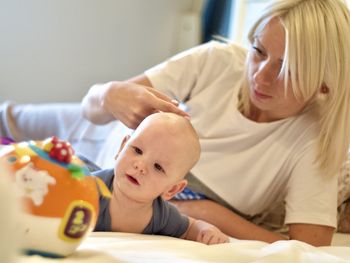 A young mum gently stroke her son's head and he stares at the toy with curiosity