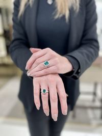 Young caucasian woman demonstrating two emerald and diamond rings on her fingers. high quality photo