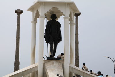 Low angle view of people standing in front of clear sky