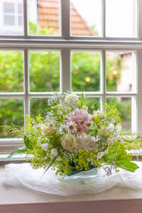 White roses in vase on table by window