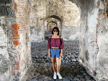 Full length of woman standing against wall