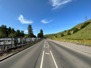 Looking along, todmorden road, with trees, caravans, fields, and a blue sky in littleborough, uk