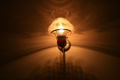 Low angle view of illuminated light bulb on wall in darkroom