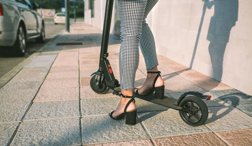 Low section of woman with bicycle on tiled floor