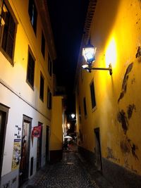 Empty alley amidst buildings in city at night