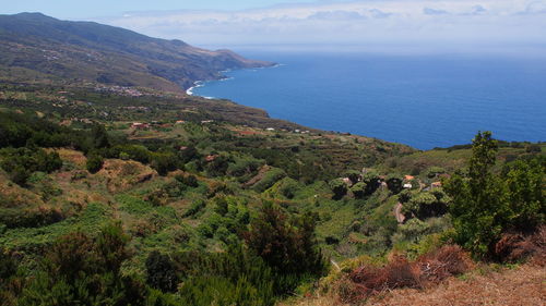 Scenic view of sea by mountains against sky