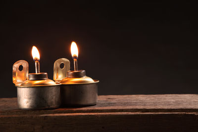 Close-up of oil lamps on wooden table against black background