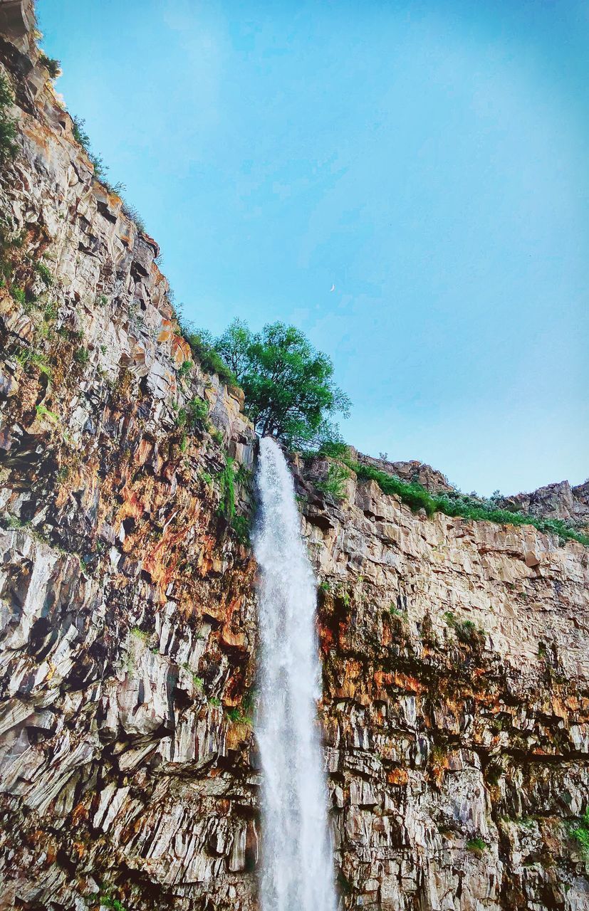 SCENIC VIEW OF WATERFALL IN MOUNTAINS AGAINST SKY