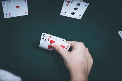 Cropped hand of woman holding cards on table