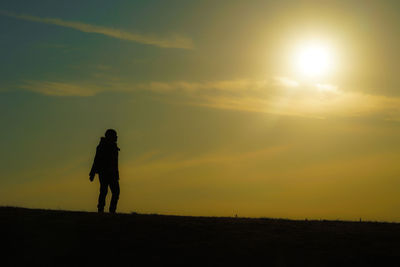 Silhouette man standing on field against sky during sunset