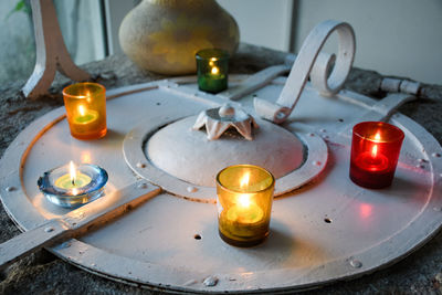 Close-up of lit tea light candles on metal 