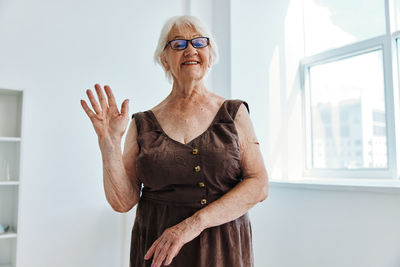 Portrait of smiling woman standing against wall