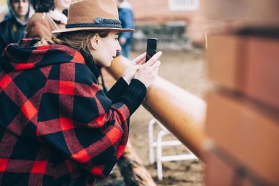 Side view of woman photographing through smart phone