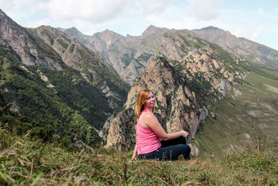 Portrait of young woman sitting against mountain range