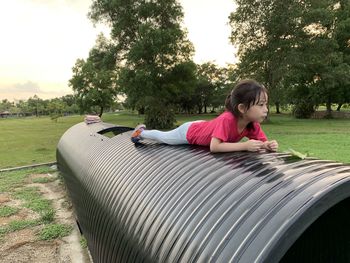 Girl sitting on field against trees