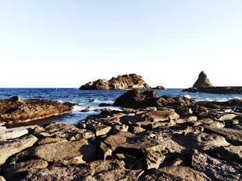 Rocks on beach against clear sky