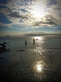 Silhouette people on beach against sky during sunset