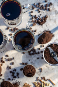 Still life with glass mugs of black hot coffee, coffee beans, ground coffee,making coffee at home