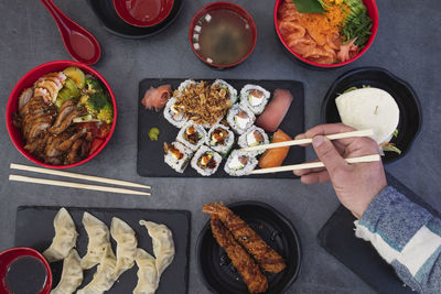  japanese food restaurant, assorted sushi platter. close up of hand with rolling chopsticks