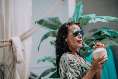 Portrait of smiling young woman holding mobile phone outdoors