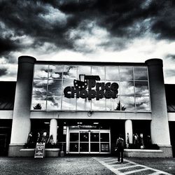 Low angle view of man walking against cloudy sky