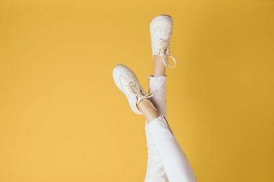 Low section of woman holding trophy against yellow background