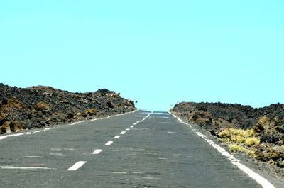Surface level of road along landscape against clear sky