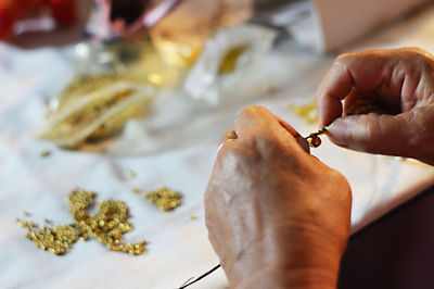 Cropped hands of man making jewelry on table