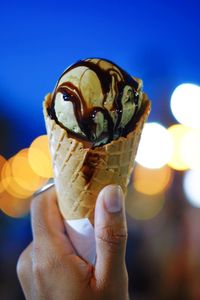 Cropped hand holding ice cream at night