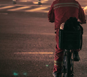 Rear view of man riding bicycle on road