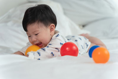 Cute girl playing with toy while lying on bed at home