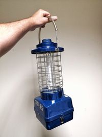 Close-up of person hand holding lantern against white wall
