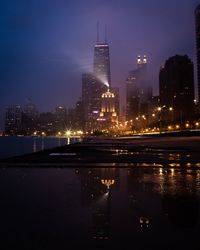 Illuminated buildings in city against sky at night