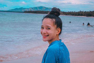 Portrait of young woman standing at beach