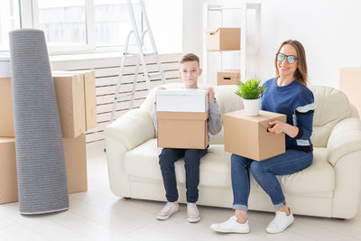 Portrait of young woman sitting in box at home