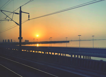 Bridge over road against sky during sunset