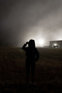 Rear view of man photographing on field against sky