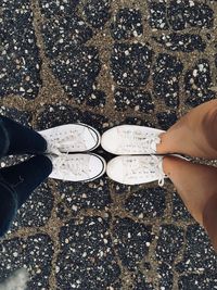 Low section of women wearing white shoes while standing on street