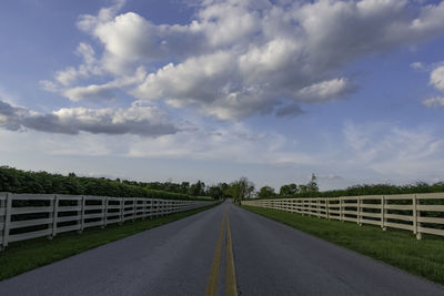 View down scenic byway in kentucky's famous bluegrass horse country with rail fences on both sides.