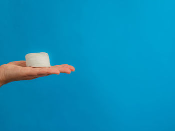 Close-up of hand holding ice cream over blue background