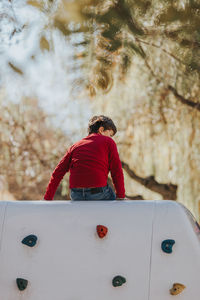 Rear view of girl standing against tree