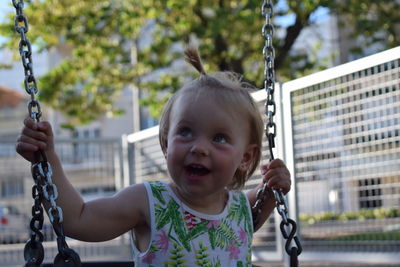 Close-up of happy girl playing on swing at playground