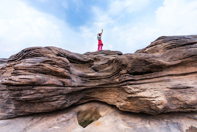 Young female tourist stands on a rock in the middle of the mekong river in the dry season