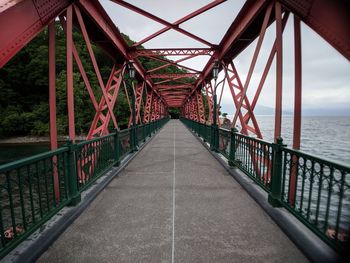 Rusty metal bridge over sea against sky